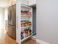 Custom slim pull-out pantry fully extended from a 12-inch gap beside a refrigerator