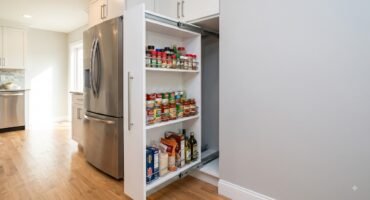 Custom slim pull-out pantry fully extended from a 12-inch gap beside a refrigerator