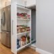 Custom slim pull-out pantry fully extended from a 12-inch gap beside a refrigerator